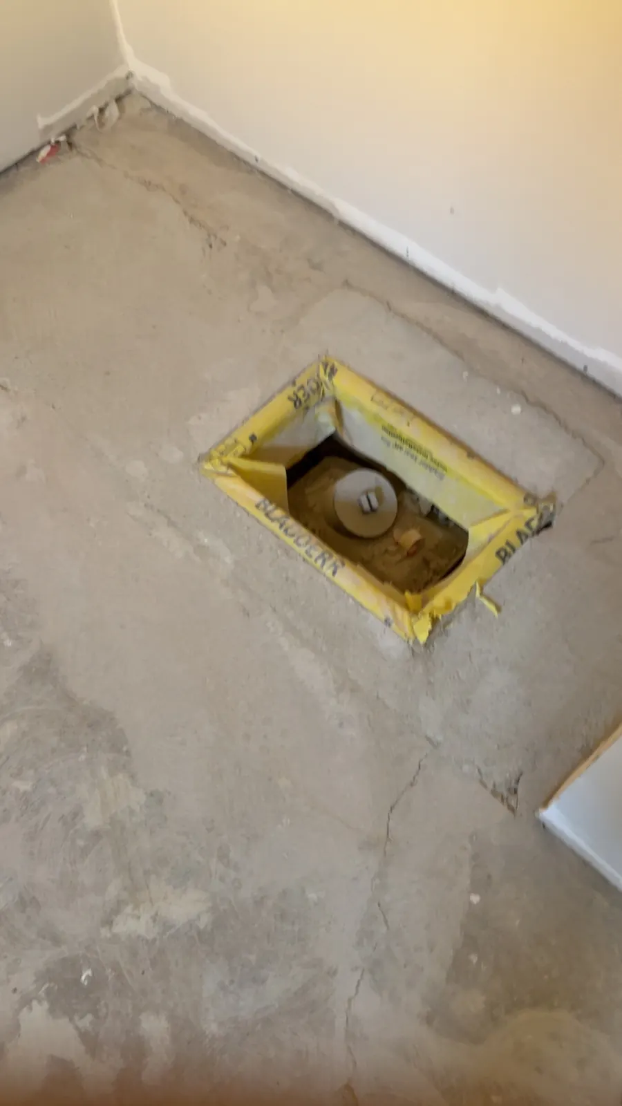 Finished backwater valve with a yellow access cover set flush in a basement concrete floor