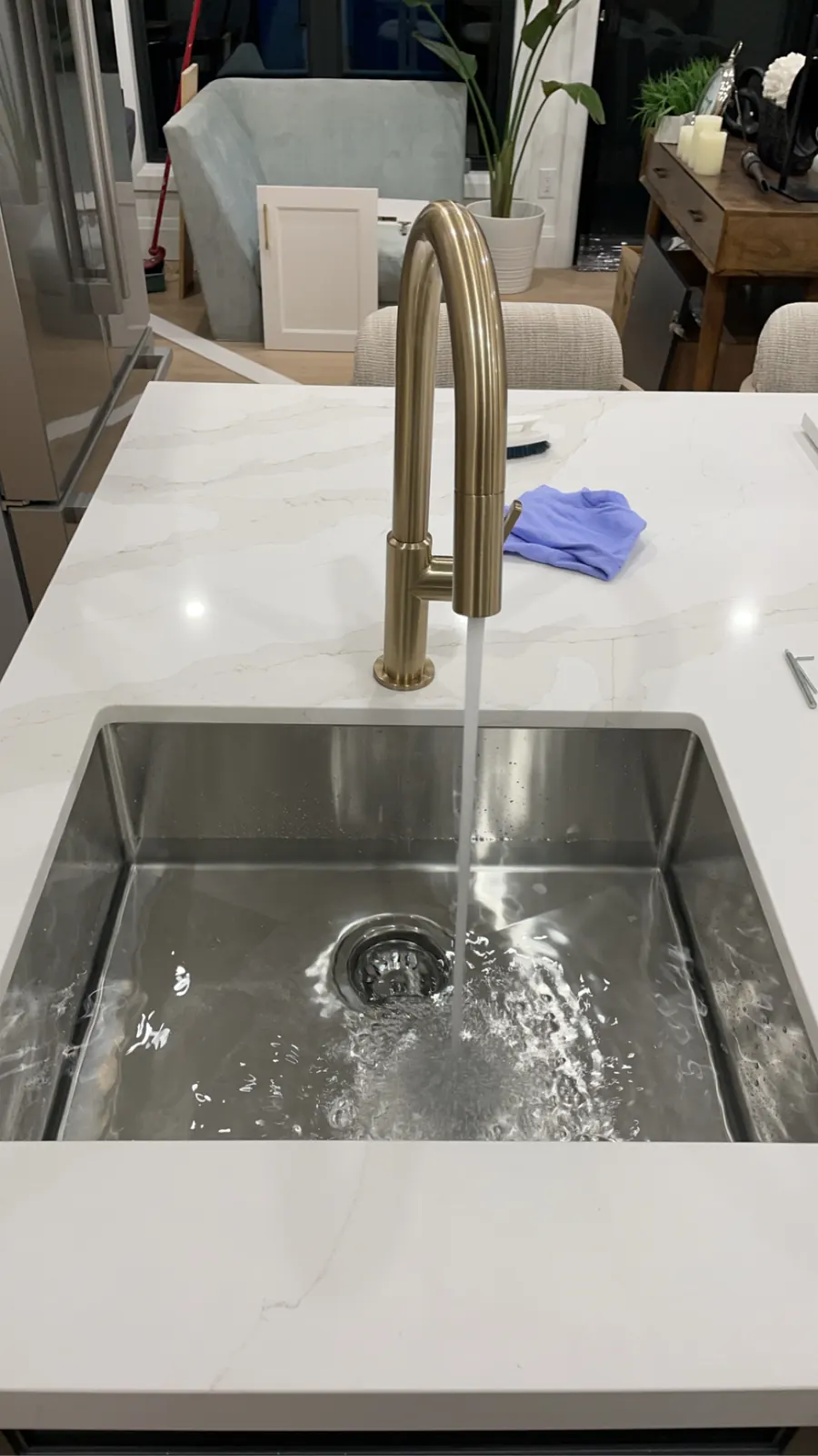 Brass kitchen faucet running into a stainless undermount sink on a kitchen island