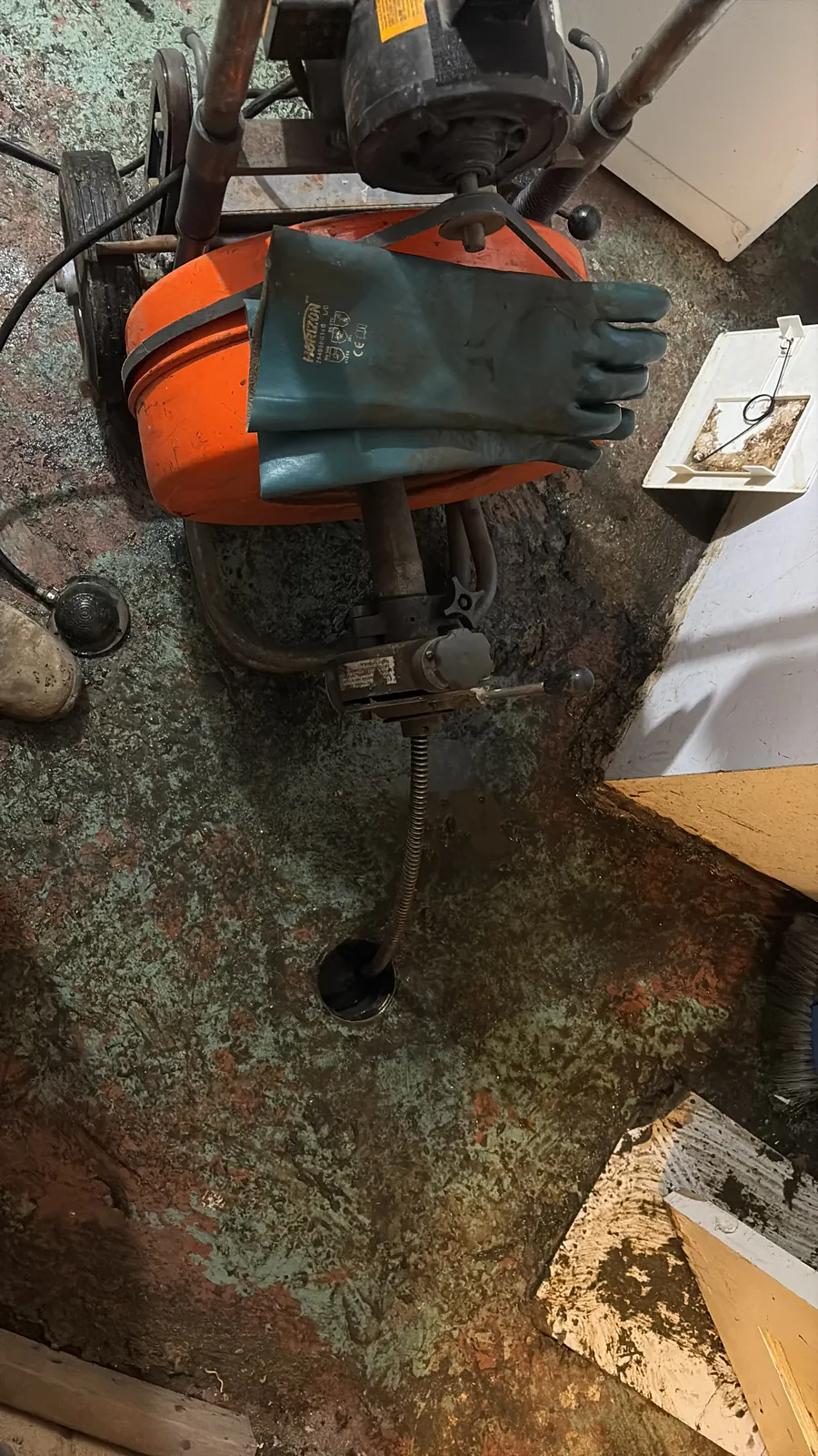 Drain cleaning machine set up over a basement floor drain
