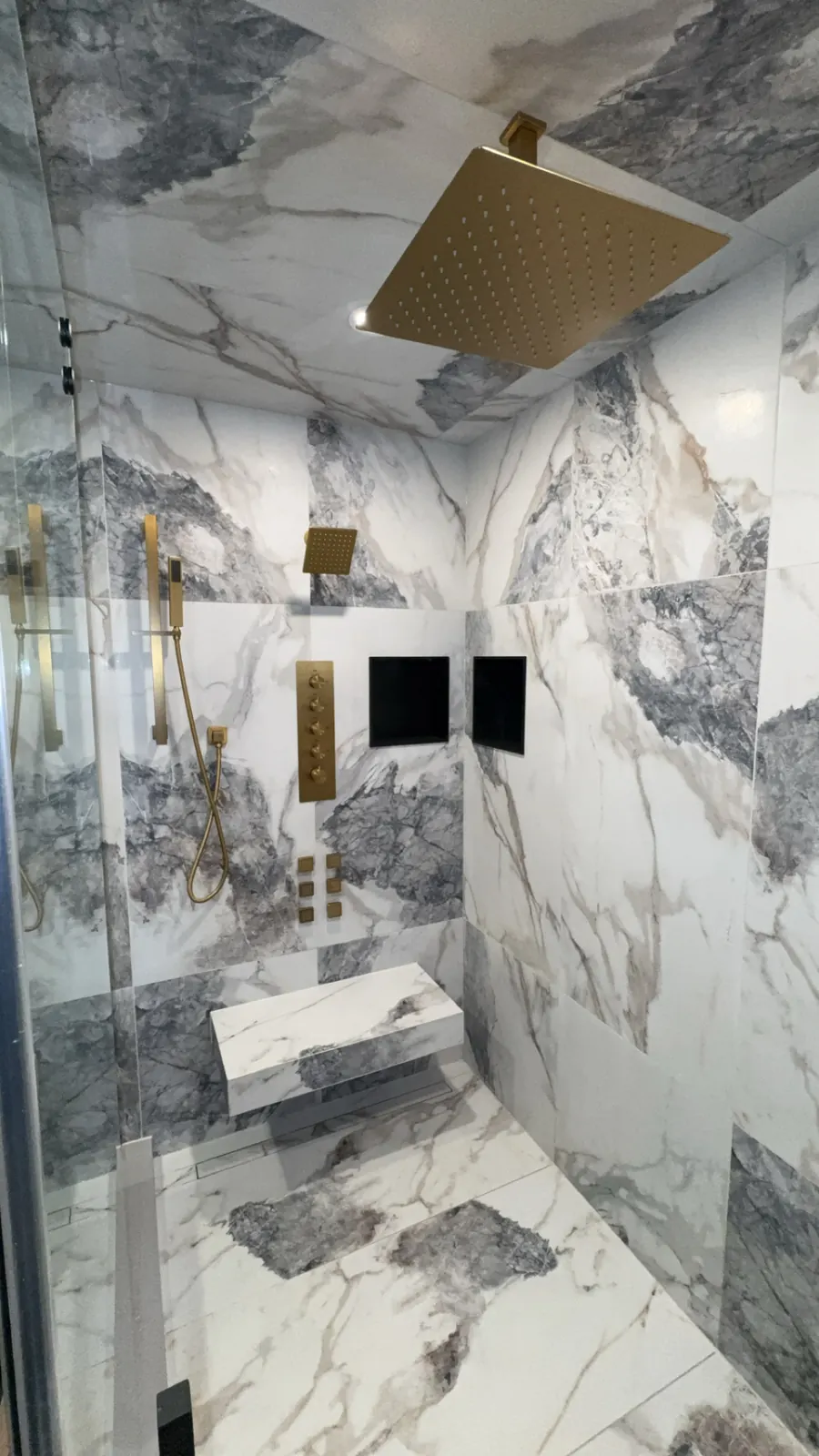 Marble walk-in shower with brass rain head and hand shower plumbed by Panacci Plumbing