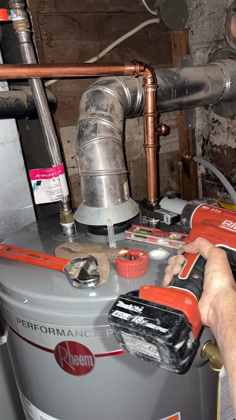 Plumber servicing the gas connection on a Rheem tank water heater